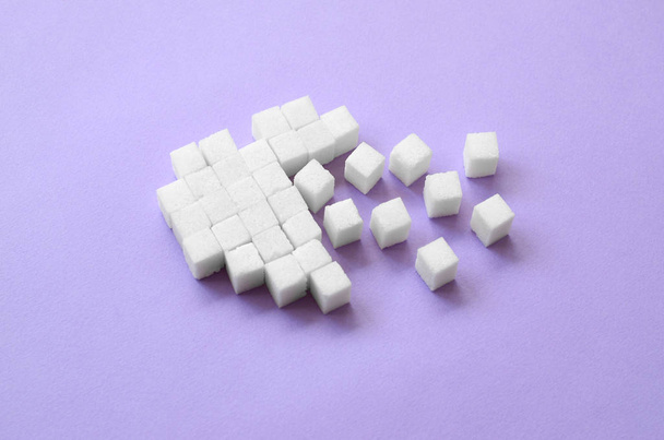 A broken heart made of sugar cubes lies on a trendy pastel violet background. - Photo, Image
