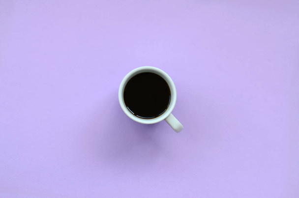 Small white coffee cup on texture background of fashion pastel violet color paper in minimal concept. - Photo, Image