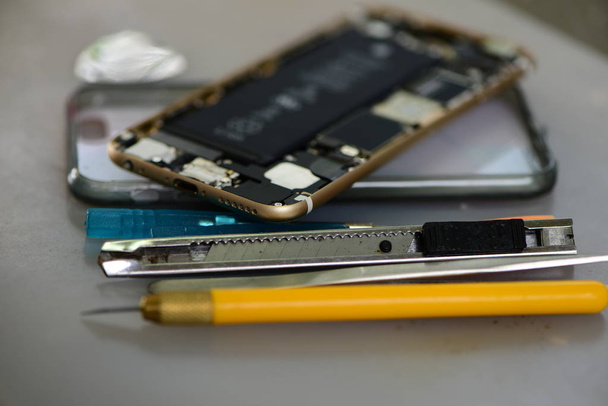Broken opened mobile phone with tools close up - Fotó, kép