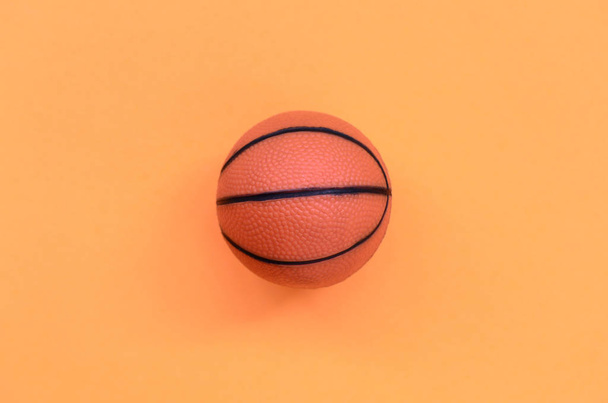 Malé oranžové koule pro basketbalové sportovní hry leží na texturu pozadí módní pastelově oranžová barva papíru v minimální koncept. - Fotografie, Obrázek