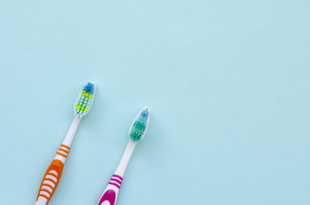 Deux brosses à dents reposent sur un fond bleu pastel. Vue de dessus, plan plat. Concept minimal
. - Photo, image
