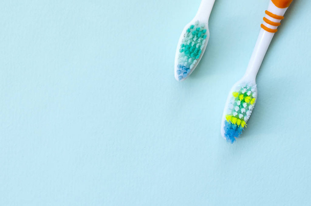 Two toothbrushes lie on a pastel blue background. Top view, flat lay. Minimal concept. - Photo, Image