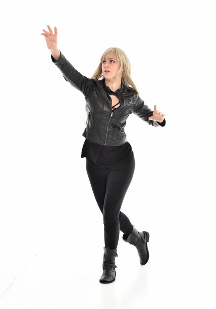 full length portrait of blonde girl wearing black leather clothes, standing pose.  isolated on white studio background. - 写真・画像