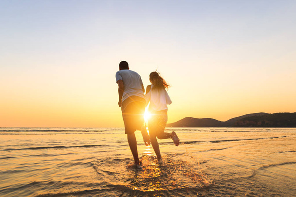 casal correndo e mão segurar na praia entre o pôr do sol
. - Foto, Imagem