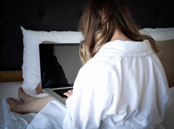 donna che utilizza un computer portatile mentre si trova a letto
 - Foto, immagini