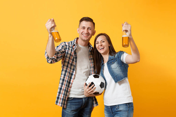 Mutlu genç çift destekçisi, kadın erkek, futbol taraftarları destek ekibi, tezahürat bira şişesi, sarı zemin üzerine izole futbol topu tutan. Spor, aile eğlence, insanların yaşam tarzı kavramı - Fotoğraf, Görsel