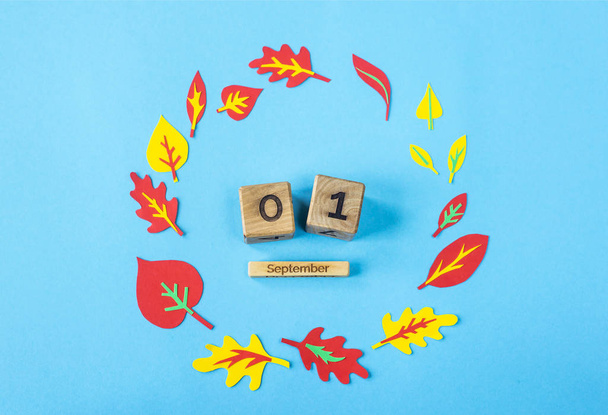 Září 1 na dřevěný kalendář na modrém pozadí mezi papír podzim listy. Podzimní pozadí - Fotografie, Obrázek