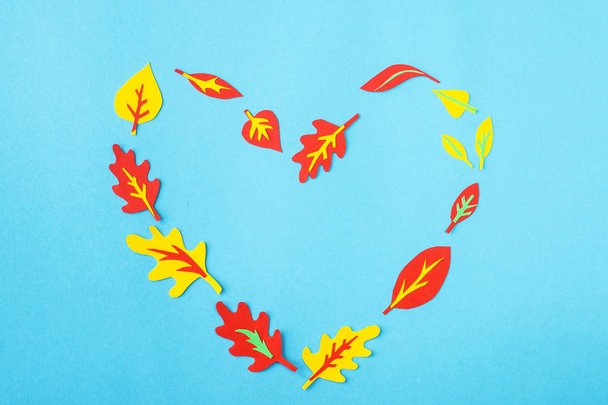 Heart made of paper applique of autumn leaves on a blue background. Autumn background - Photo, Image