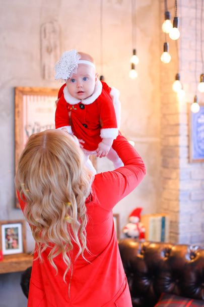 Femme blonde gardant bébé féminin portant des vêtements rouges
. - Photo, image