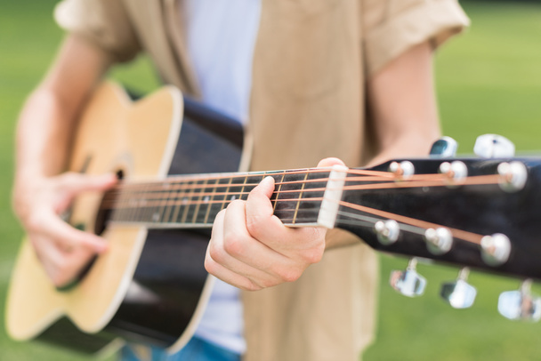 cropped shot of man playing acoustic guitar in park - Fotografie, Obrázek
