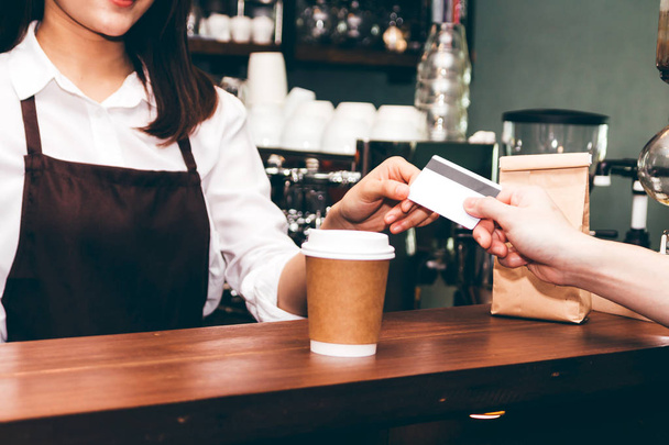Barista donna che prende una carta di credito dal cliente in caffetteria
 - Foto, immagini