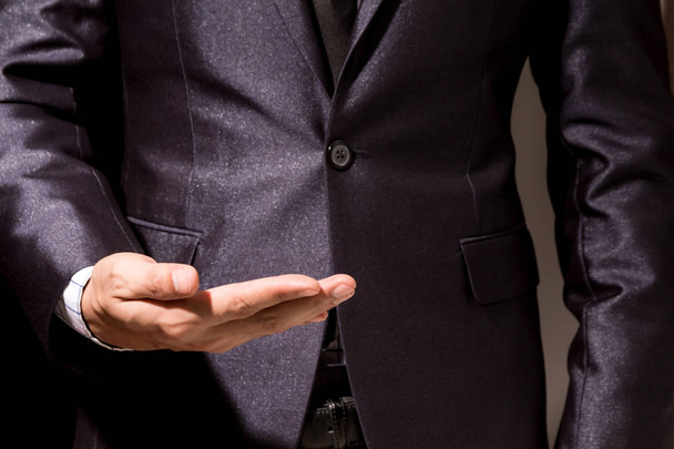 Geschäftsmann zeigt leeren Kopierraum auf offener Hand auf schwarzem Hintergrund - Foto, Bild