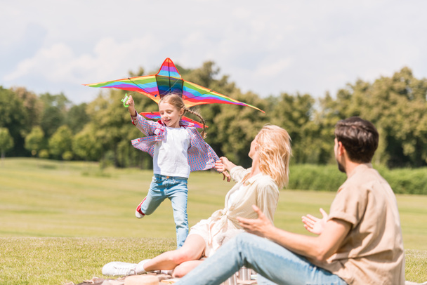 happy family with one child playing with colorful kite in park - Foto, immagini