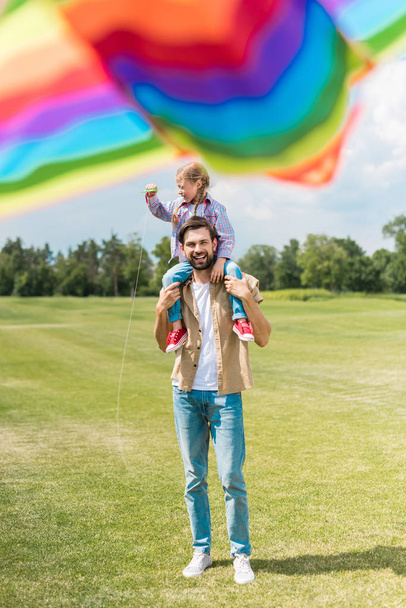 selective focus of happy father and daughter playing with colorful kite in park - Zdjęcie, obraz