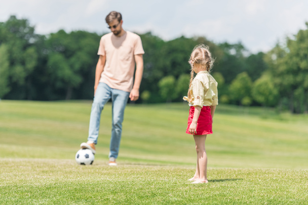 father and cute little daughter playing with soccer ball on lawn - Fotoğraf, Görsel