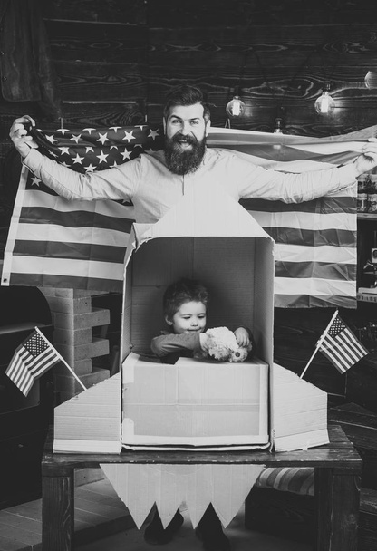 American dream. American cheerful family with usa flags play with rocket made out of cardboard box. Kid happy sit in hand made rocket with usa flags. Child cute boy play cosmonaut, astronaut. Rocket - Фото, зображення