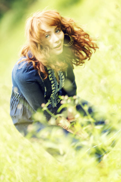 Beautiful red-haired woman in a Boeho style dress in a field - Fotoğraf, Görsel