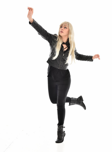 полноразмерный портрет блондинки в черной кожаной одежде, стоящей позы. изолированные на белом фоне студии
. - Фото, изображение