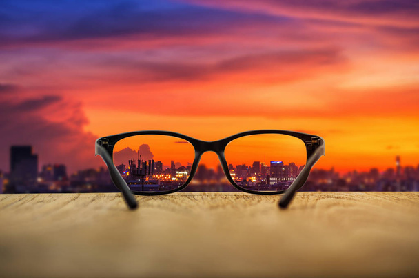 Cidade clara focada em lentes de óculos com fundo de paisagem urbana turva
. - Foto, Imagem