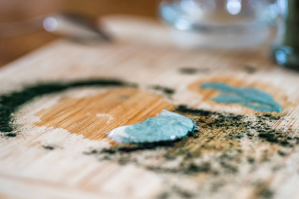 Вид крупным планом свежий кефир пробиотик напиток и зеленый спирулина порошок остатки на деревянной доске после смешивания на кухонном столе
 - Фото, изображение