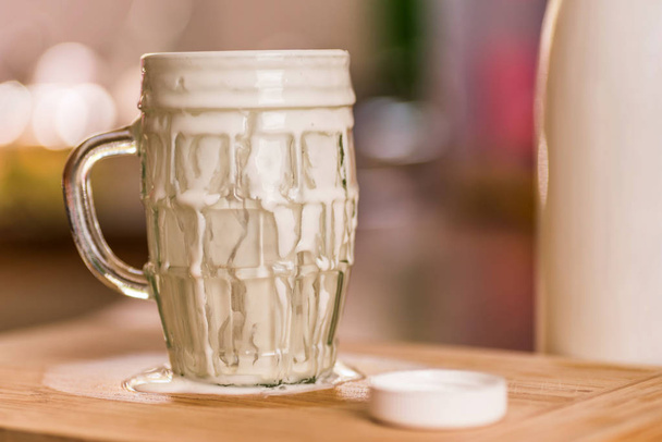 Detailní pohled čerstvý kefír probiotik nápoj se vynořil z přeplněna prázdnou sklenici na kuchyňském stole - Fotografie, Obrázek