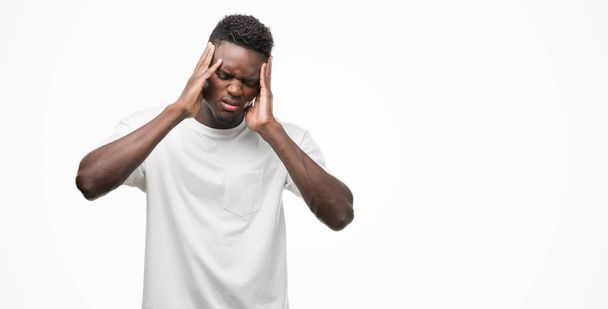 Jovem afro-americano vestindo camiseta branca com a mão na cabeça para a dor na cabeça porque o estresse. Enxaqueca que sofre
. - Foto, Imagem