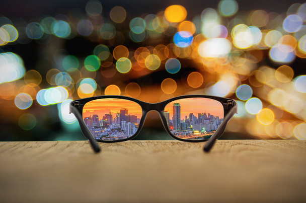 ぼやけている街並みの背景を持つ眼鏡レンズで焦点を当てて明確な都市の景観. - 写真・画像