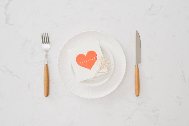 love dinner setting fork and spoon tie with red ribbon on plate on white background , love and romance concept - Photo, Image