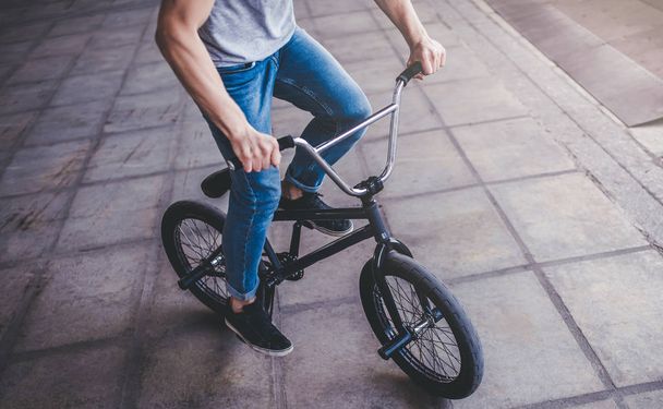 Cropped image of young man in skatepark. Male teenager with BMX bike. Professional BMX rider. - Zdjęcie, obraz