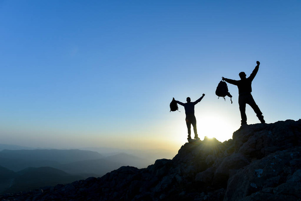 Wanderer mit Rucksack steht mit erhobenen Händen auf einem Berg und genießt die Aussicht - Foto, Bild