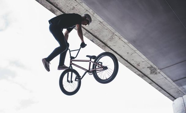 Tiener Bmx rider is het uitvoeren van trucs in skatepark. - Foto, afbeelding