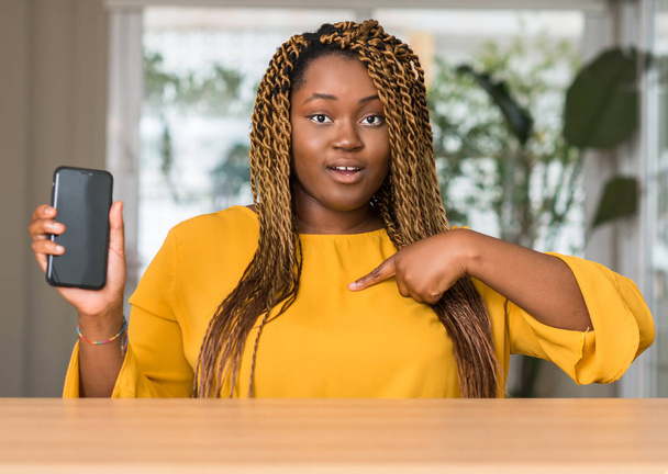 donna afroamericana utilizzando smartphone con faccia a sorpresa puntando il dito verso se stesso
 - Foto, immagini