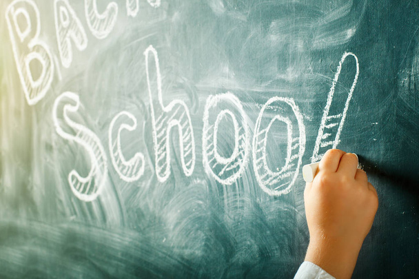 A child writes with a chalk on a blackboard. Back to school background - Zdjęcie, obraz