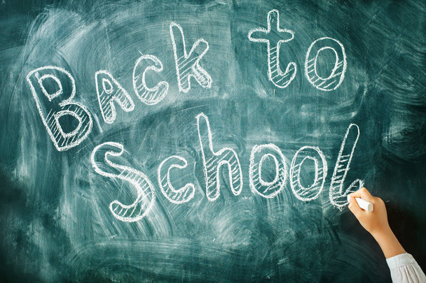 A child writes with a chalk on a blackboard. Back to school background. - Foto, Imagen