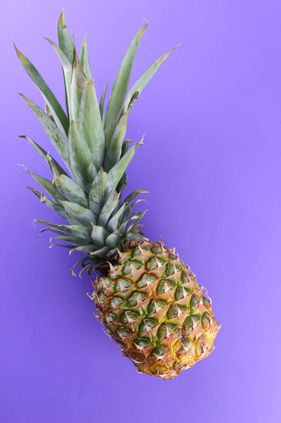 Pineapple on purple background, exotic fruit top view, pineapple for designer in pop art style, vegetarian food in minimalism style, copy space - Фото, зображення