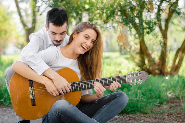 Young girl having fun while learning to play guitar from her male friend - Fotoğraf, Görsel