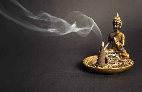 Buddha Räucherstäbchenhalter mit brennendem Kegel und Rauch. Meditation und Yoga-Atmosphäre - Foto, Bild