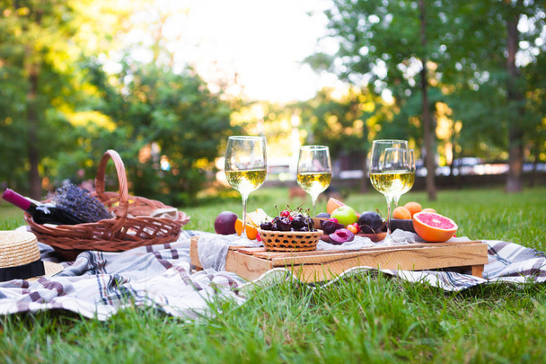 Picknick-Hintergrund mit Weißwein und Sommerfrüchten auf grünem Gras - Foto, Bild