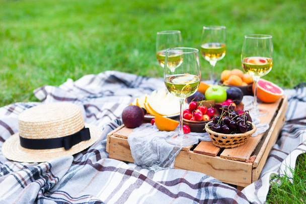 Picnic background with white wine and summer fruits on green grass - Foto, Imagen