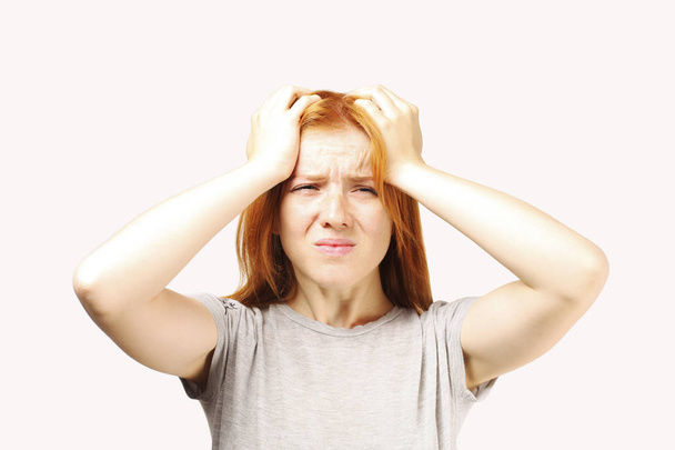 Beautiful redheaded young woman experiencing severe migraine writhing with pain. Pretty female feeling headache holding head. Nonverbal behavior, body language. White background, close up, copy space. - Photo, Image