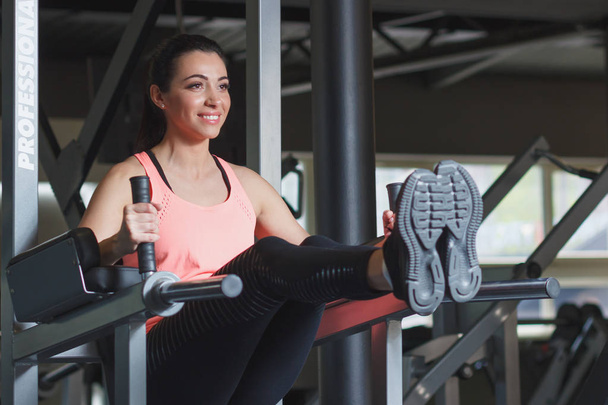 Sporty young woman makes sport exercises in the gym, soft focus background - Fotografie, Obrázek