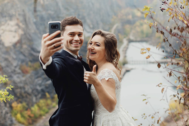 Boldog newlywed pár véve selfie gyönyörű kilátás nyílik a nyári hegyi folyó. - Fotó, kép