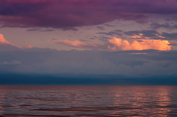 Grandes nubes de tormenta en el mar de Azov, iluminadas por el sol poniente, el horizonte del mar. Reflexión sobre la superficie del agua
. - Foto, Imagen