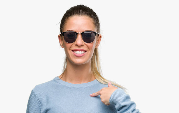Красива молода жінка в сонцезахисних окулярах і хвіст з несподіваним обличчям вказуючи палець на себе
 - Фото, зображення