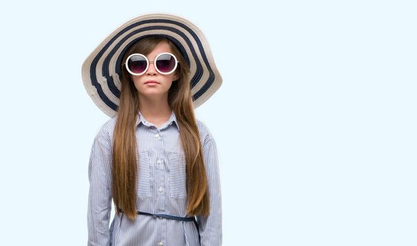 Nuori blondi lapsi yllään hattu ja aurinkolasit luottavainen ilme älykäs kasvot ajattelu vakava
 - Valokuva, kuva
