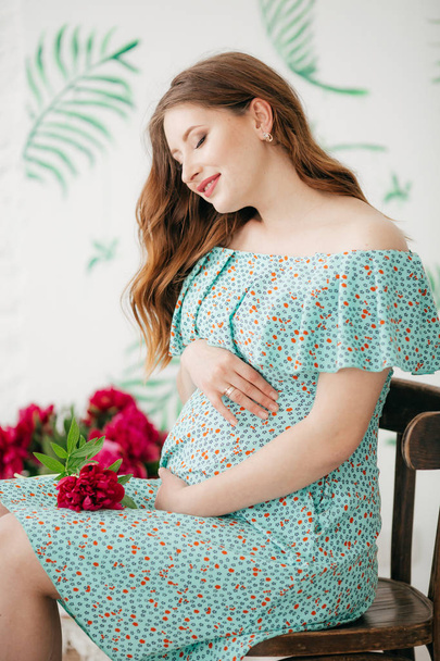 Mooie zwangere vrouw in blauwe jurk met bloemen - Foto, afbeelding