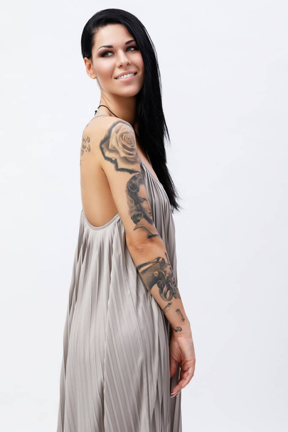 Woman with tattoos wearing beautiful dress in studio - Foto, imagen