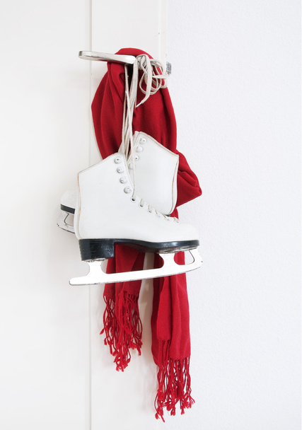 Lady skates and red scarf hanging on white door - Foto, immagini