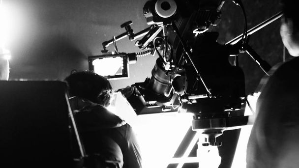 シルエットの人のぼやけた画像映画プロ機器のカメラで映像を撮影し、スタジオの照明のシーンの背後に働く乗組員チーム. - 写真・画像