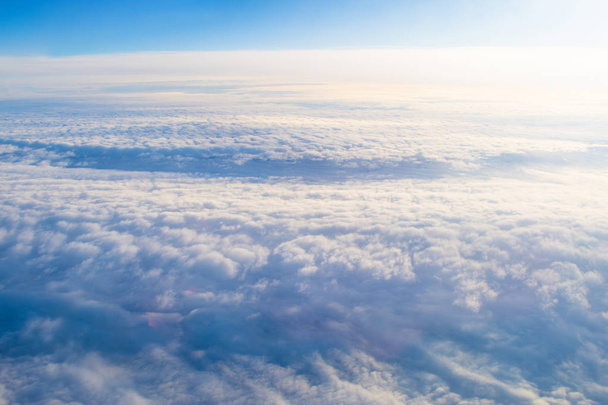 bewölkt mit Höhenflug des Flugzeugs, glatte gleichmäßige Struktur des weißen Dampfes vor dem Sonnenuntergang - Foto, Bild